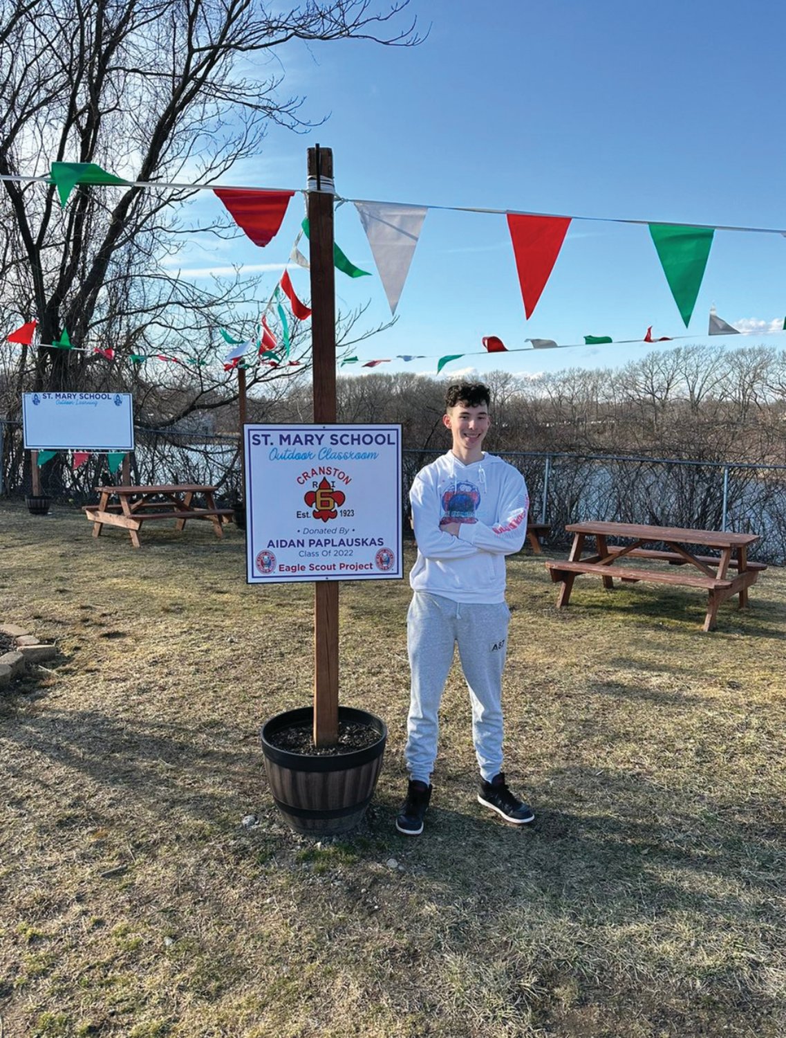 ALL FIXED UP: Eagle Scout Aidan Paplauskas posed for a photo with the freshly scrubbed outdoor classroom sign at St. Mary’s School. He built the classroom and erected the sign. The sign was vandalized, but Paplauskas went to work immediately cleaning up the site.